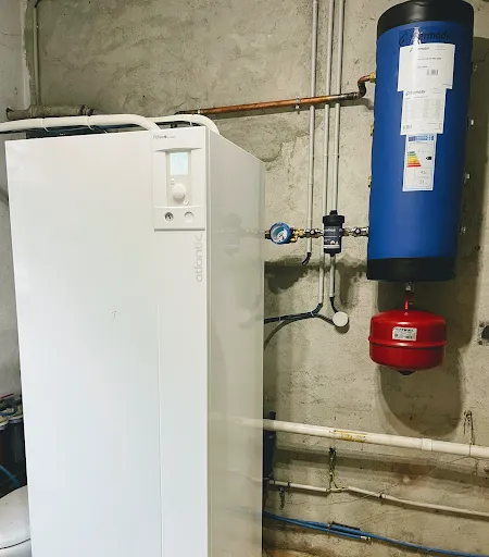 Module intérieur Atlantic posé au sol, avec un ballon tampon bleu et un vase d'expansion rouge fixés au mur