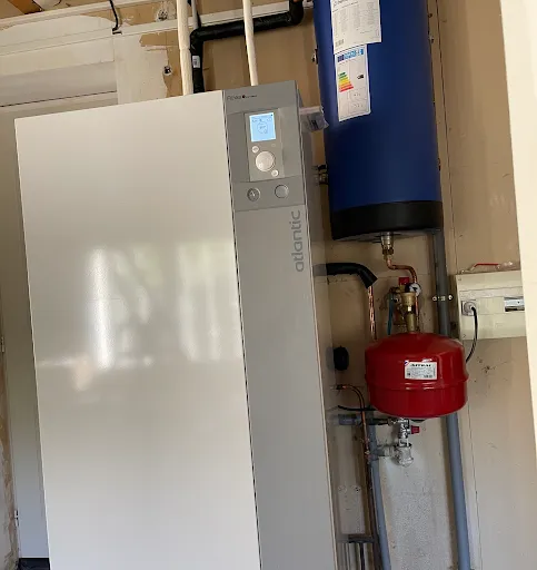 Module intérieur Atlantic gris et blanc posé au sol, avec un ballon bleu et un vase d'expansion rouge au mur