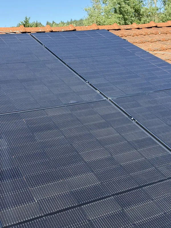 Gros plan sur des panneaux photovoltaïques noirs full black fixés côte à côte sur une toiture en tuiles canal, Calmont, juillet 2025