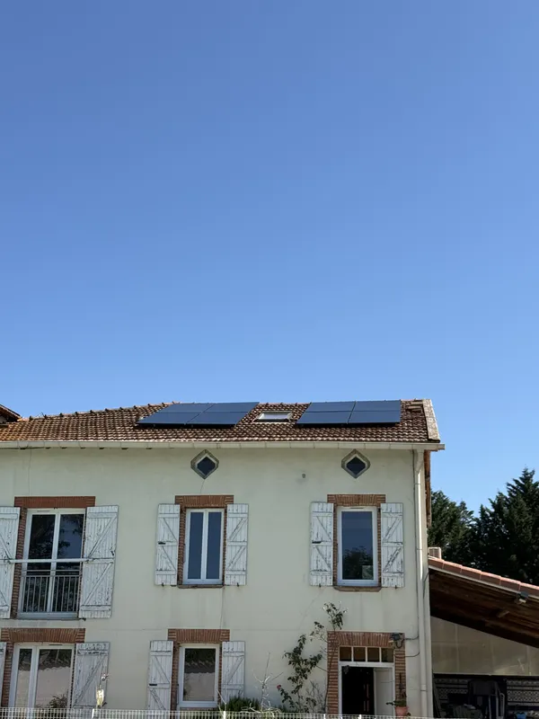Façade d'une maison à Calmont avec, sur le toit, deux champs de quatre panneaux photovoltaïques de part et d'autre d'une fenêtre de toit